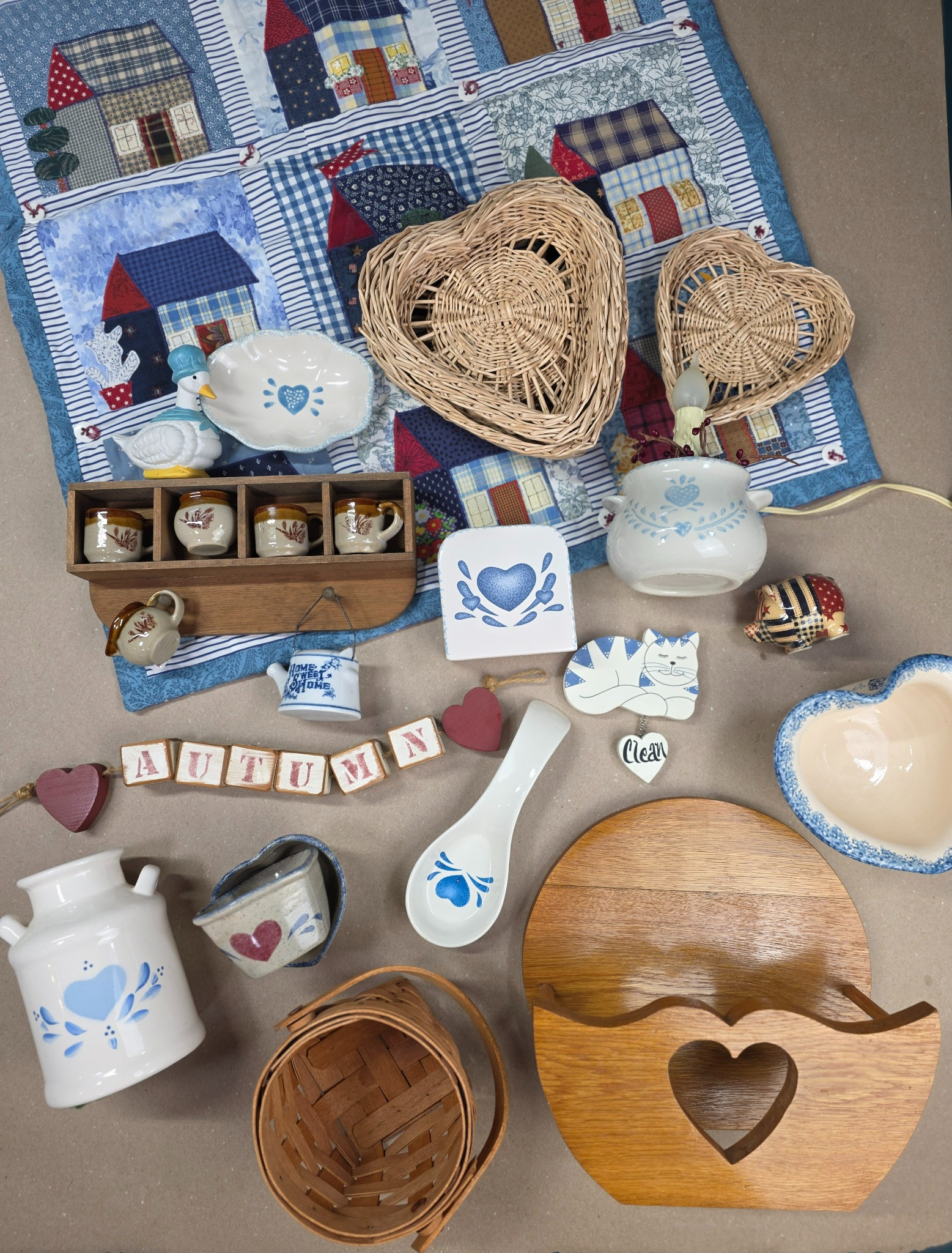 Homespun Hearts flat lay with blue country décor, wicker hearts, quilted houses, and an oak heart cutout holder